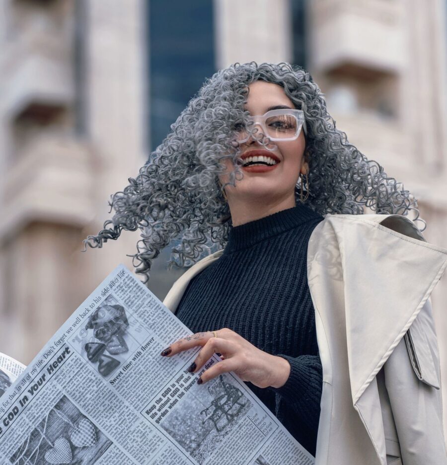 Woman with grey hair, holding a newspaper.