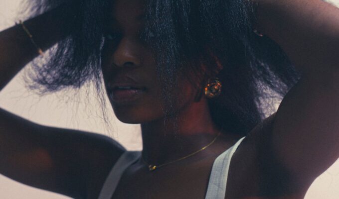 Woman with her hands in her hair, pulling it upwards.