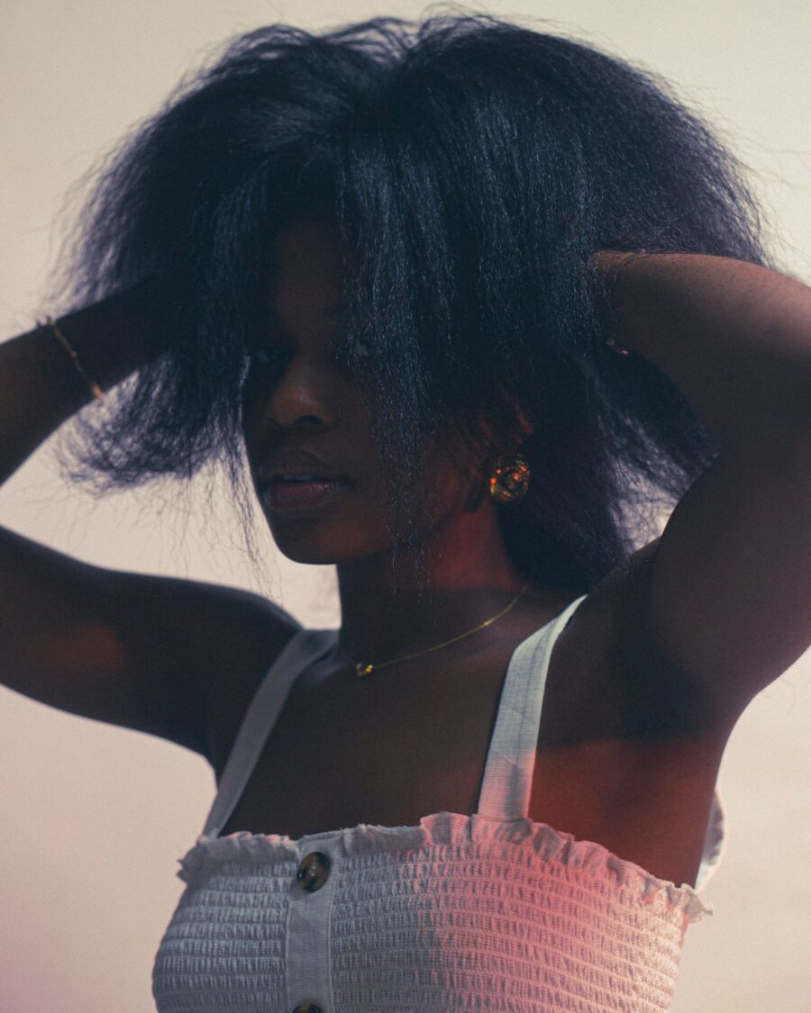 Woman with her hands in her hair, pulling it upwards.