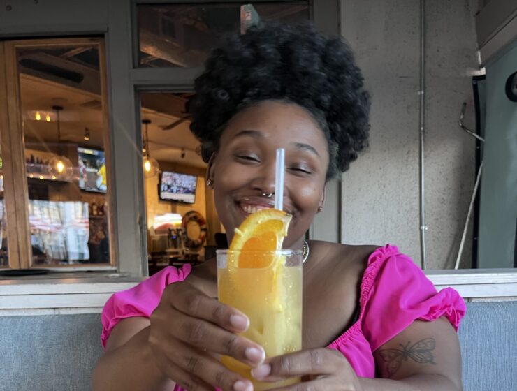 Woman holding a mixed drink, smiling at the camera.