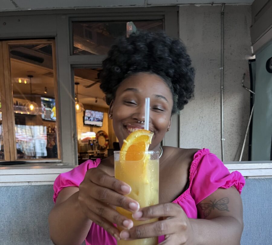 Woman holding a mixed drink, smiling at the camera.
