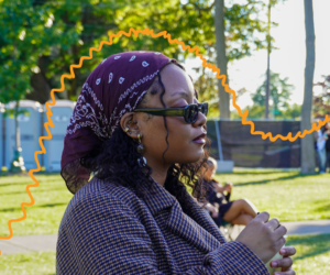 Woman with purple bandana, listening to music at some kinda festival.