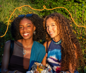 Two friends with curly hair, smiling.